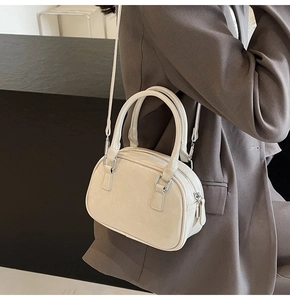 Detail of a minimalist cream white PU leather Boston bag with slim shoulder strap