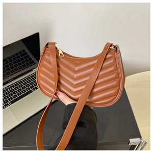 Brown V-quilted faux leather crescent shoulder bag with golden zipper in a casual setting