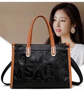 Détail des coutures contrastées et lettres embossées sur le sac cabas noir et marron