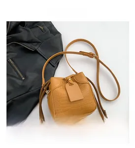 Detail showing yellow crocodile embossed bucket bag with drawstring closure and shoulder strap