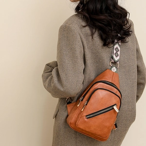 Detail of vintage brown chest bag with layered zippers and ethnic pattern woven strap