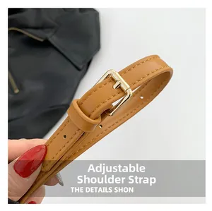Close-up of adjustable brown PU leather shoulder strap with golden metal buckle and stitching