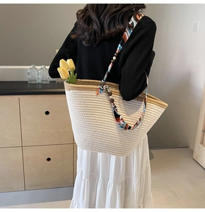 Detail view of woven tote bag featuring floral silk scarf strap and wooden bead accents