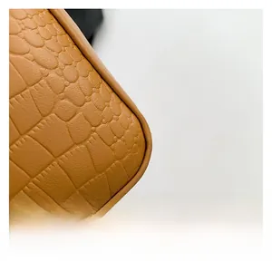 Detailed macro view of the brown crocodile embossed texture and stitching on the bag