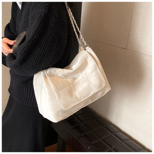 Détail d'un sac à bandoulière blanc matelassé avec chaîne en métal argenté brillant