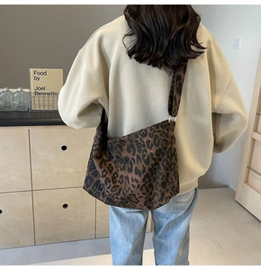 Détail d'un sac bandoulière tendance à imprimé léopard avec large bandoulière porté par mannequin