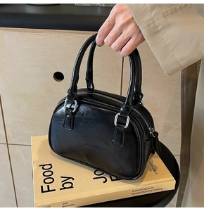 Close-up of black glossy mini handbag with silver zipper on a wooden cabinet