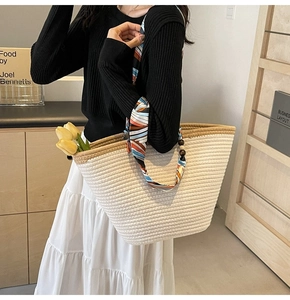 Detail of woven tote bag with silk scarf handle and wooden bead accents in interior setting