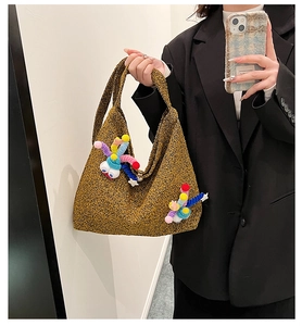 Detail of yellow tweed crossbody bag featuring whimsical plush eye and star charms