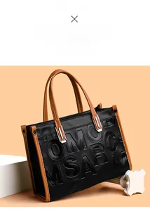 Détail du cabas en cuir grainé noir avec logo OMC MSARCM embossé et bandoulières marron