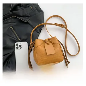 Detail of crocodile pattern bucket bag with drawstring and leather shoulder strap