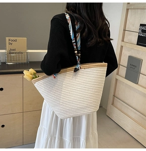 Detail of off-white woven tote bag with printed satin handle and wooden bead accents