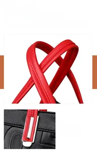 Détails du cuir grainé noir et des poignées rouges sur un sac à main bandoulière chic