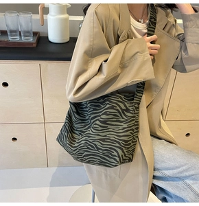 Détail du sac bandoulière en toile zébrée vert foncé et noir porté par un mannequin