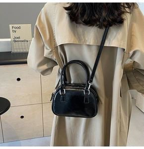 Detail of high-gloss black PU leather shoulder bag with silver hardware on a model