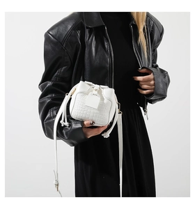 Close-up of a white crocodile texture bucket bag with drawstring closure and slim strap