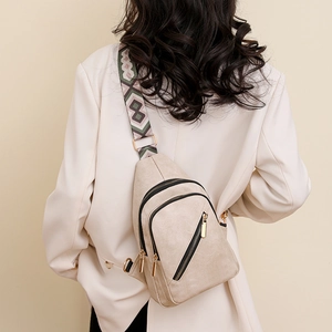 Detail of beige faux leather crossbody bag with three zippers and geometric strap