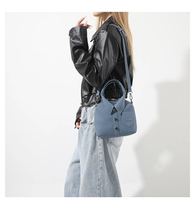 Dettaglio della borsa a secchiello blu-grigio con design a camicia e bottoni sulla modella