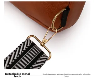 Close-up of detachable gold metal hook and woven geometric shoulder strap on brown leather bag