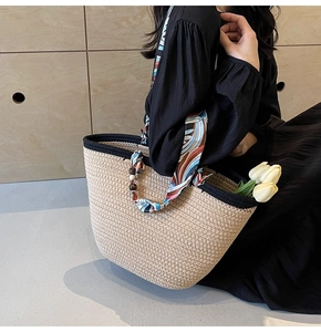Detail of woven straw tote bag featuring silk scarf handle and wooden beads decor