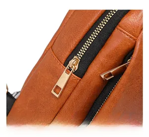 Detail view of premium brown lychee leather texture and smooth golden hardware zippers