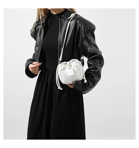 Detailed view of white crocodile pattern mini crossbody bag worn with a black leather jacket