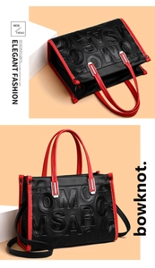 Détail du sac cabas rouge et noir avec lettres gaufrées et boucle argentée