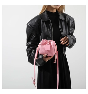 Detail of pink croc-embossed mini bucket bag with drawstring closure and slim strap