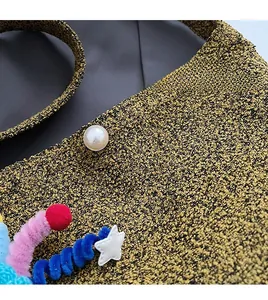 Close-up of textured bouclé bag with pearl button and colorful plush star charms