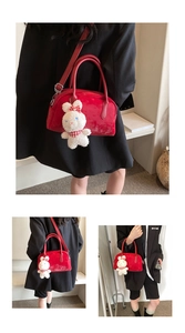 Dettaglio borsa Boston rossa con ciondolo a coniglietto di peluche bianco e tracolla
