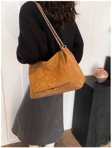 Détail d'un sac cabas marron en similicuir matelassé avec une bandoulière en chaîne