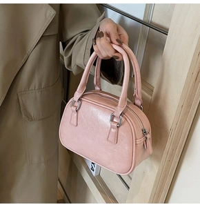 Pink PU leather Boston handbag held by model in trench coat showing style and size