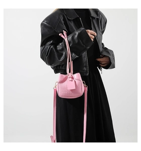 Detailed macro view of pink crocodile textured PU leather handbag with drawstring closure