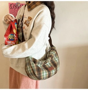 Detail view of plaid wool crescent bag with brown textile strap in a lifestyle setting