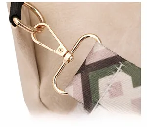 Détail du crochet pivotant doré sur sac beige avec bandoulière à motif géométrique