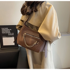 Detail of brown litchi pattern leather shoulder bag with gold chain and front zip pocket