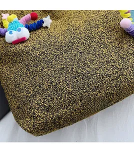 Close-up view of textured black and gold tweed fabric on a stylish shoulder bag
