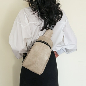 Detailed shot of beige PU leather sling bag with geometric jacquard wide strap on model