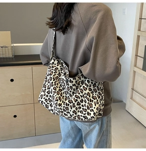Détail d'un grand sac cabas en toile à imprimé léopard porté à l'épaule pour femme
