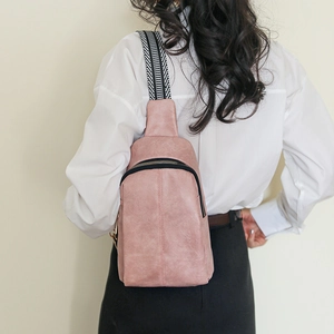 Close-up of pink leather sling bag with trendy black and white striped woven strap