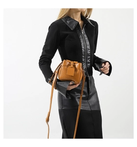 Detail of tan crocodile texture bucket bag with drawstring and long shoulder strap
