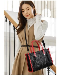 Détail du sac bandoulière noir et rouge avec lettres embossées et texture en cuir chic