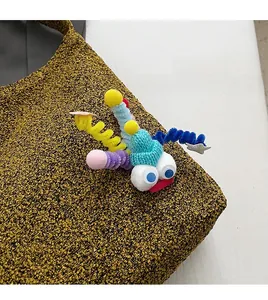Detail of creative handmade colorful cartoon pendant on yellow textured crossbody bag