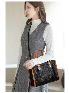 Détail du sac cabas noir avec liseré orange et texture gaufrée porté par un mannequin