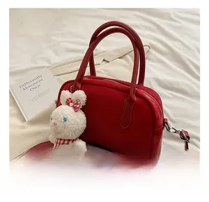 Dettaglio della borsa rossa in similpelle con ciondolo a coniglio bianco e manico tondo