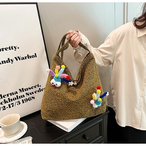 Detail view of yellow textured winter tote bag featuring colorful plush doll ornaments
