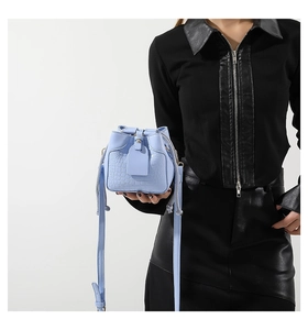 Detail of light blue croc-embossed mini bucket bag with drawstring and shoulder strap