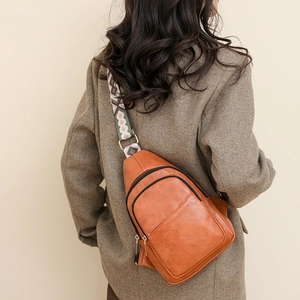 Détail d'un sac bandoulière en cuir marron avec une large sangle tissée au style ethnique chic