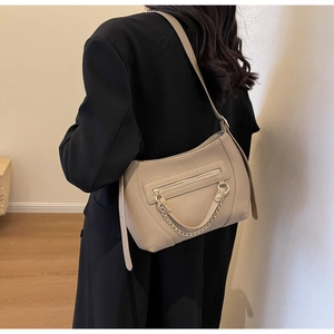 Detail view of beige lychee texture shoulder bag with metal chain on female model