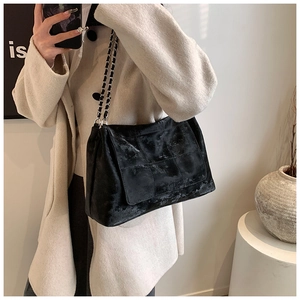 Gros plan d'un sac bandoulière noir matelassé en cuir PU avec chaîne sur le modèle